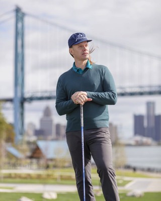 Professional golfer Jaacob Bowden, PGA stands atop Riverside Park with the Ambassador Bridge and downtown Detroit in the background