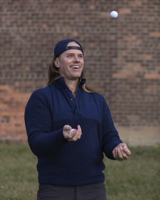 Jaacob Bowden juggles golf balls in front of a brick building in the Hubbard Richard neighborhood of Detroit
